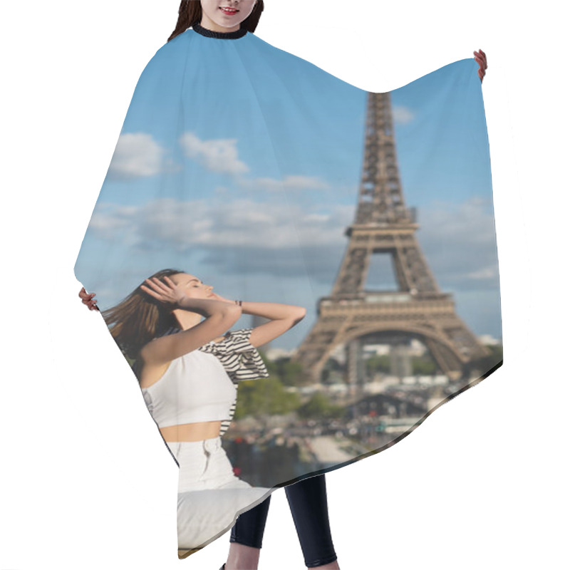 Personality  Young Woman With Closed Eyes Adjusting Hair And Sitting Near Eiffel Tower In Paris  Hair Cutting Cape