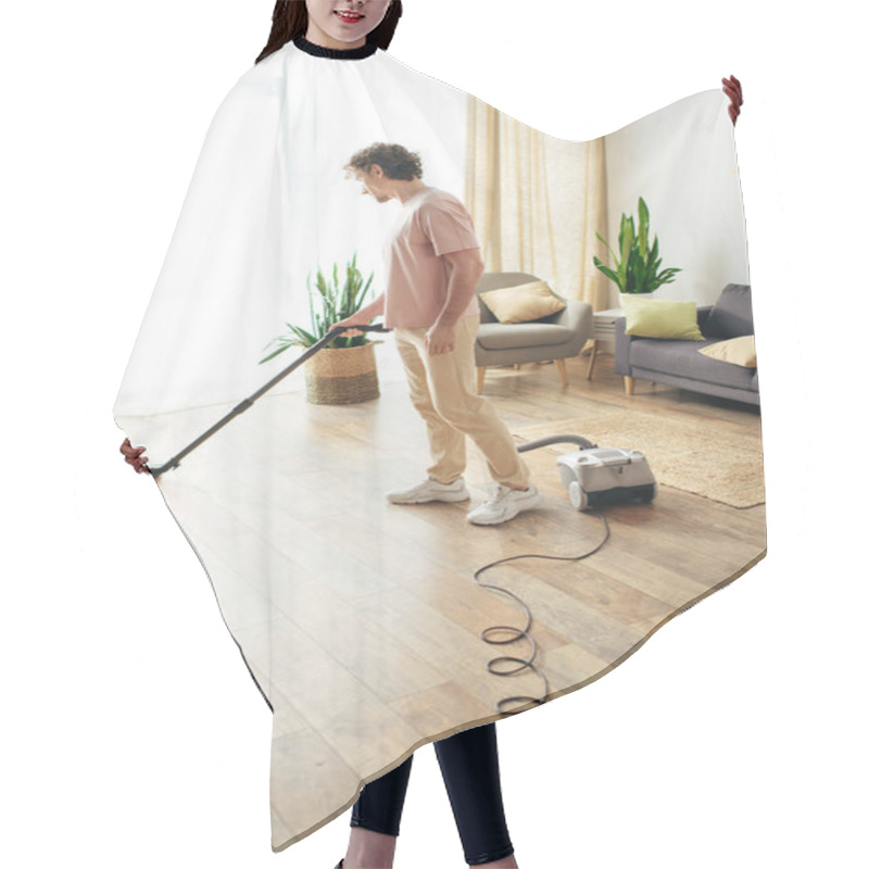 Personality  A Handsome Man In Cozy Homewear Cleans The Floor Using A Vacuum. Hair Cutting Cape