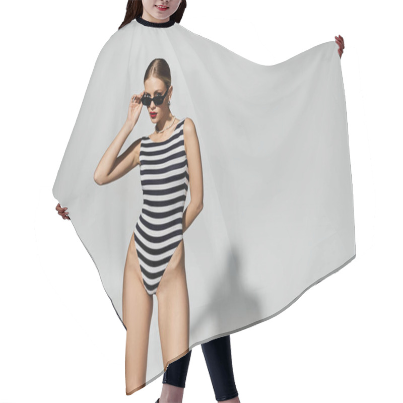 Personality  A Fashionable Blonde Woman In A Black And White Striped One-piece Swimsuit. Hair Cutting Cape