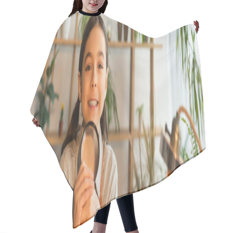 Personality  Cheerful Girl Holding Magnifying Glass And Looking At Camera Near Blurred Lamp At Home, Banner  Hair Cutting Cape