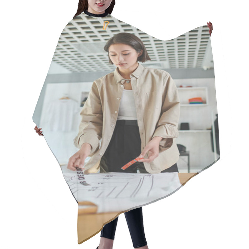 Personality  Young Female Asian Designer Holding Text Template Near Clothing With Format Sizes In Print Studio Hair Cutting Cape