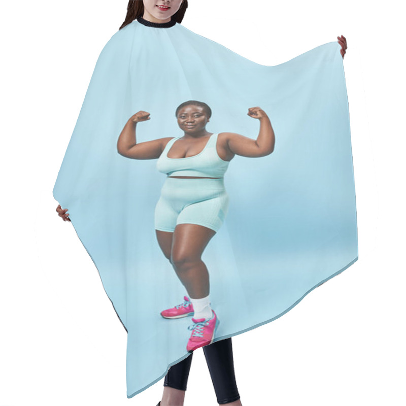 Personality  Strong Plus Size Woman In Active Wear Flexing Her Muscles And Looking At Camera On Blue Background Hair Cutting Cape