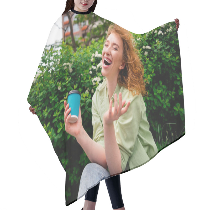 Personality  A Cheerful Young Female Student With Red Hair Laughs Heartily While Sitting Outdoors On A Sunny Day, Holding A Coffee Cup Amidst Lush Greenery. Hair Cutting Cape