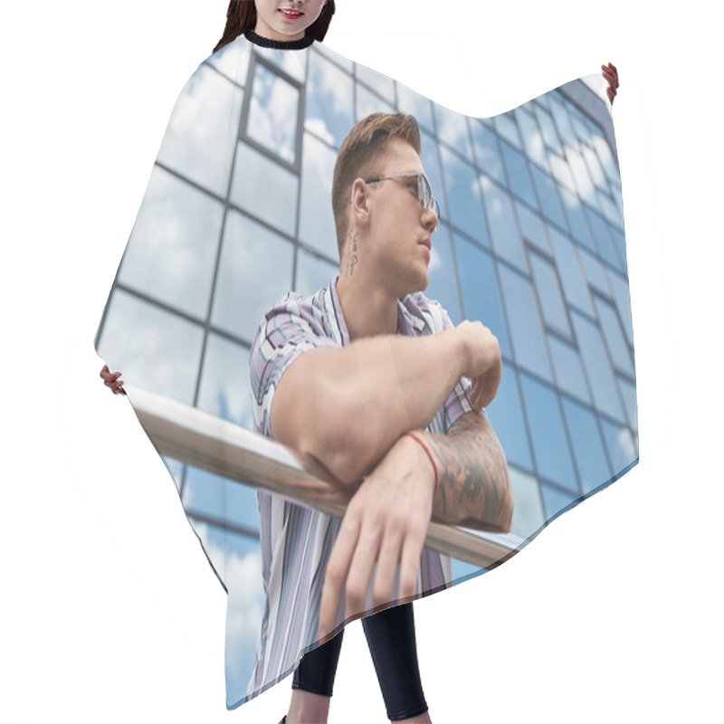 Personality  A Young Man With Tattoos Stands Confidently By A Sleek Glass Building. Hair Cutting Cape