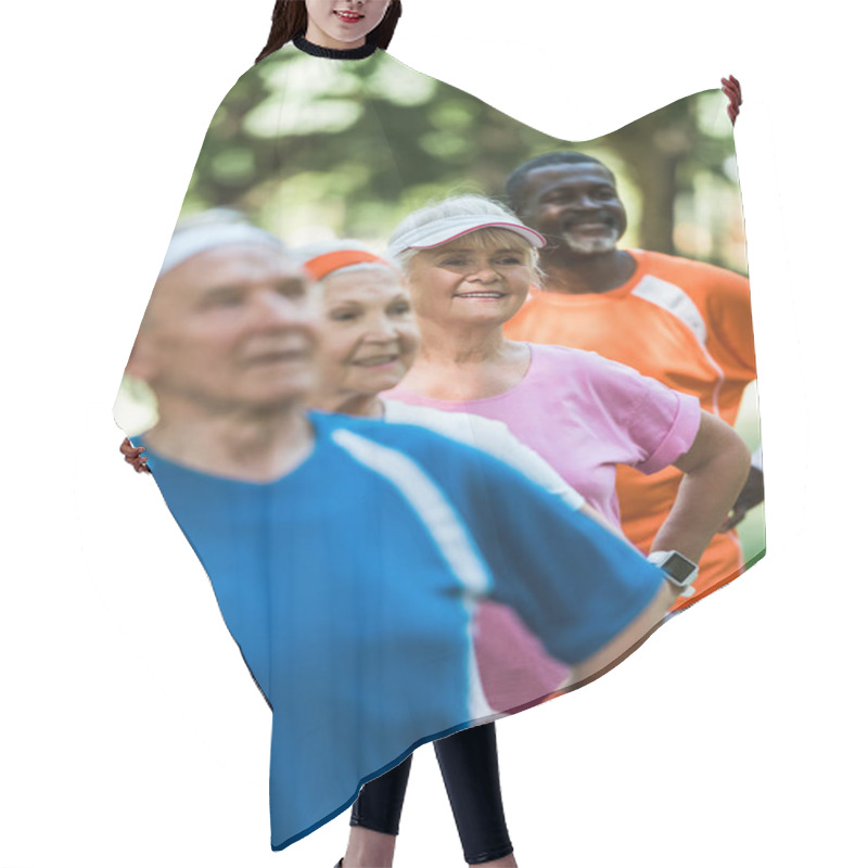 Personality  Selective Focus Of Cheerful Retired African American Man Standing With Hands On Hips With Pensioners In Sportswear  Hair Cutting Cape