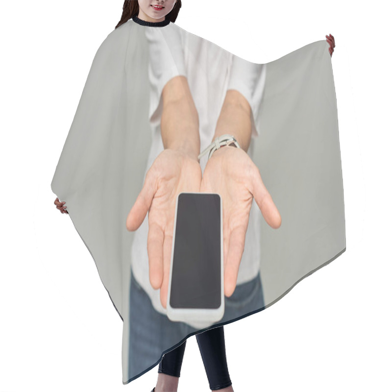 Personality  Cropped View Of Person Holding Mobile Phone With Blank Screen On Grey Backdrop, Smartphone In Hands Hair Cutting Cape