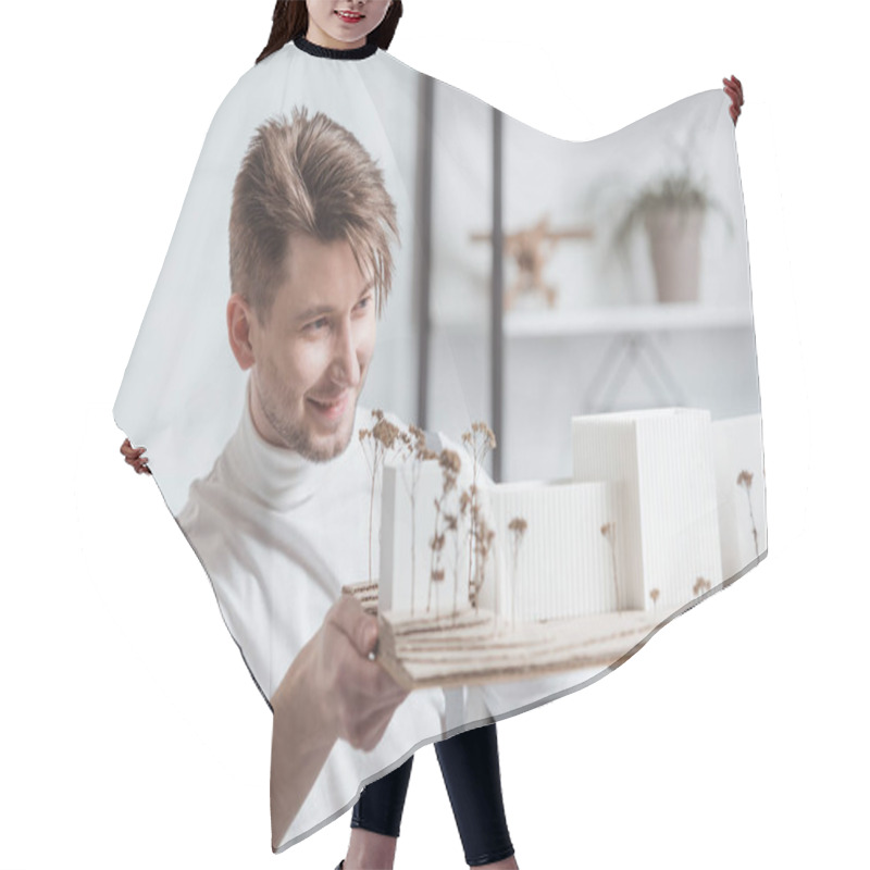 Personality  Portrait Of Smiling Architect Looking At Self Made Building Model In Hands In Office Hair Cutting Cape