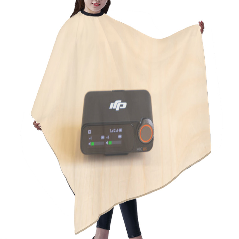 Personality  Bishkek, Kyrgyzstan - November 4, 2024: DJI MIC 2 Receiver With Display Interface Showing Audio Levels And Settings On A Wooden Surface Hair Cutting Cape