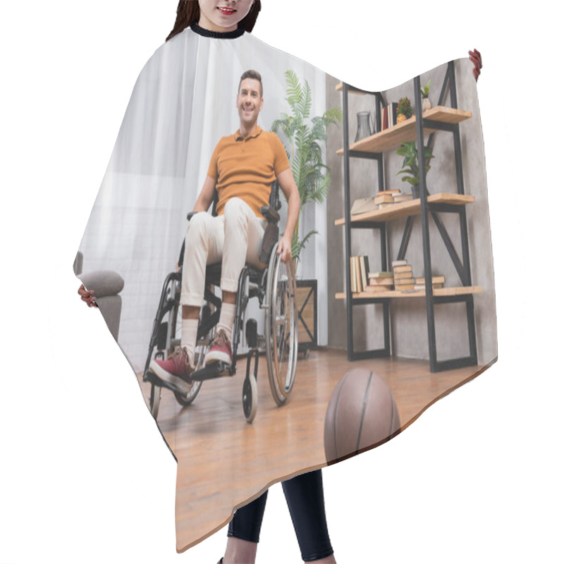 Personality  Joyful Man Smiling At Camera While Sitting In Wheelchair Near Basketball On Floor Hair Cutting Cape