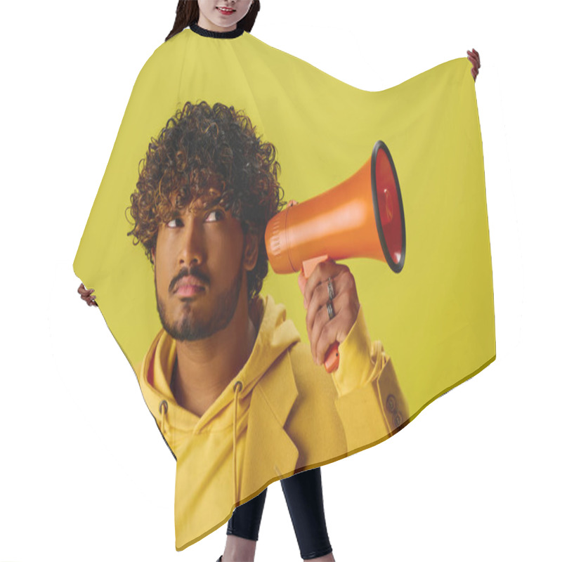 Personality  A Handsome Young Indian Man In A Yellow Hoodie Holding A Red Megaphone. Hair Cutting Cape