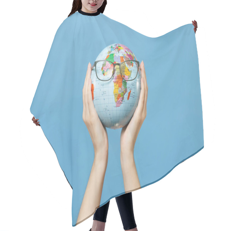 Personality  Close Up Female Hold In Hands Geographic Political World Globe With Glasses Isolated On Blue Background. Learning About Countries. Education In High School University Concept. Travel Journey Abroad Hair Cutting Cape