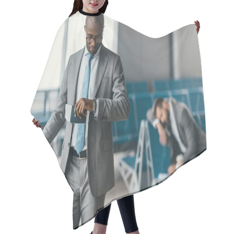 Personality  Handsome Businessman Looking At Watch While Waiting For Flight In Airport Lobby With Sleeping Man Blurred On Background Hair Cutting Cape