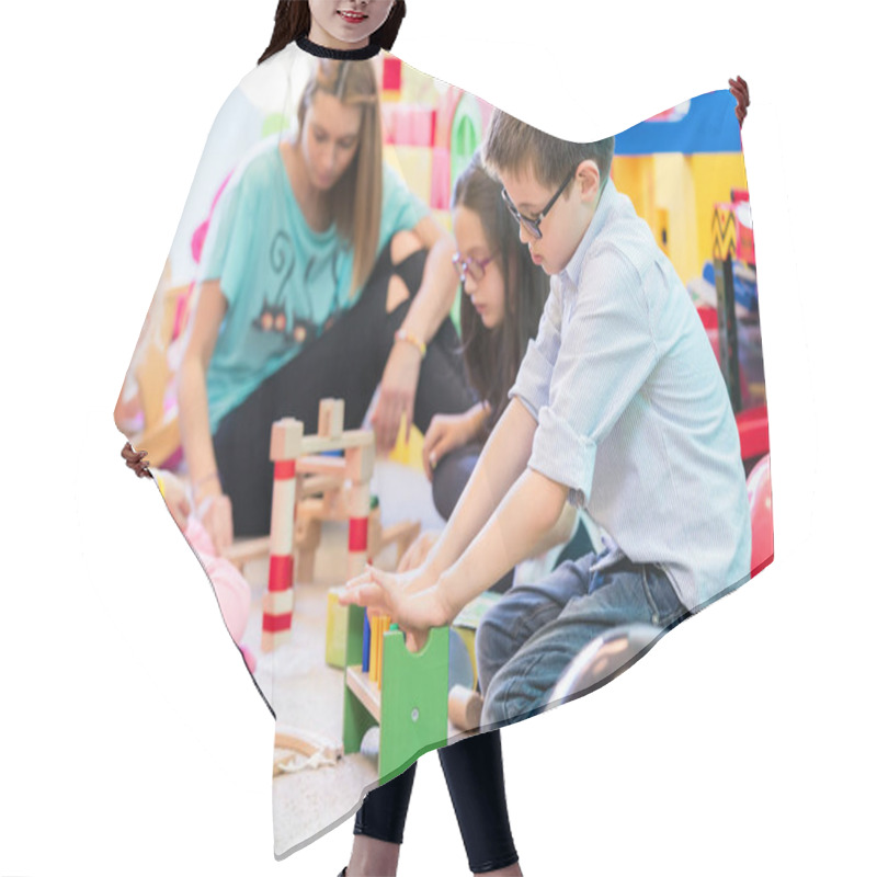 Personality  Cute Pre-school Boy Cooperating With His Colleagues At The Construction Of A Structure Made Of Wooden Toy Blocks, Under The Guidance Of A Young Kindergarten Teacher Hair Cutting Cape