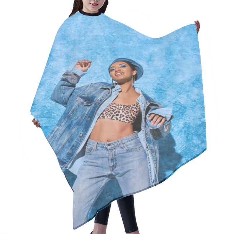 Personality  Low Angle View Of Fashionable Young African American Model In Beret Posing In Top And Denim Clothes While Smiling At Camera On Blue Textured Background, Stylish Denim Attire Hair Cutting Cape