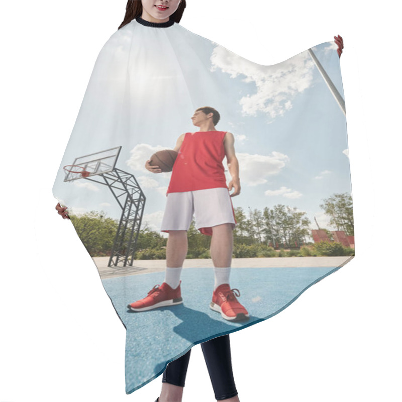 Personality  A Young Basketball Player Stands On The Court, Holding A Basketball, Ready To Play In The Summer Heat. Hair Cutting Cape