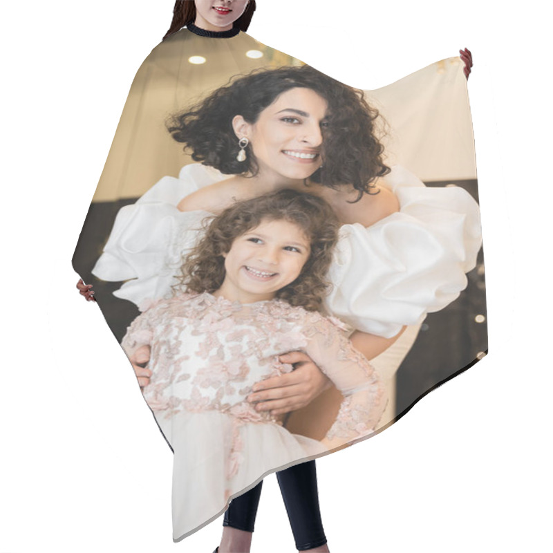 Personality  Gorgeous Middle Eastern Bride With Brunette Hair Standing In White Wedding Dress With Puff Sleeves And Ruffles Behind Cute Daughter And Smiling Together In Bridal Store, Looking At Camera  Hair Cutting Cape