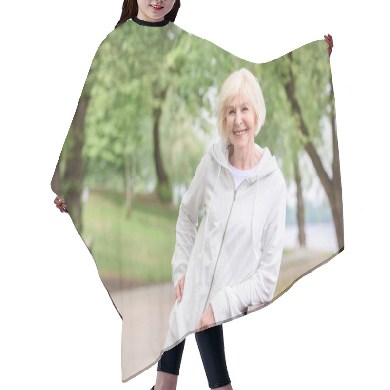 Personality  Smiling Senior Woman Standing Near Railings In Park Hair Cutting Cape