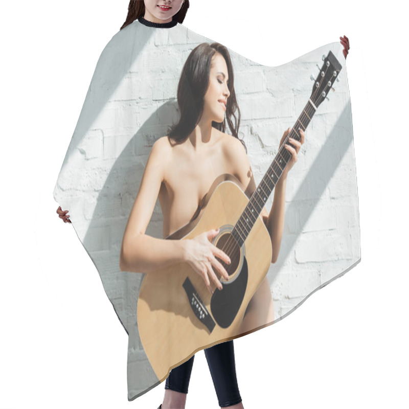 Personality  Beautiful Naked Woman Smiling While Playing Acoustic Guitar Near White Brick Wall At Home  Hair Cutting Cape