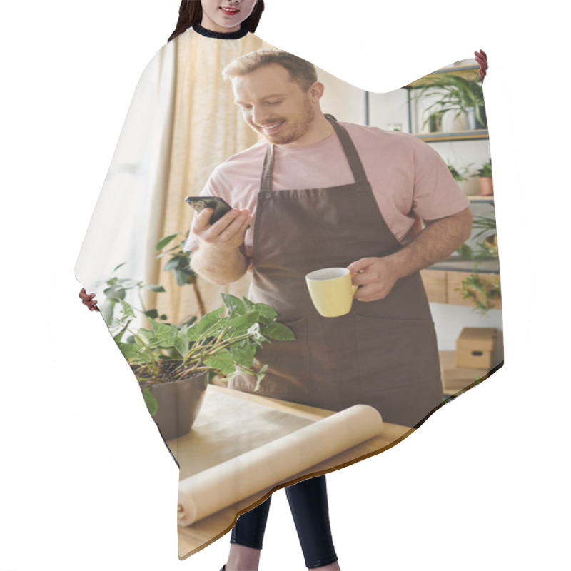 Personality  Man In Apron Holding Cup, Checking Phone In Small Plant Shop. Business Owner Multitasking During Busy Day. Hair Cutting Cape