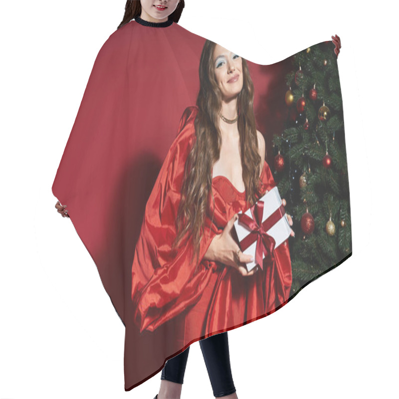 Personality  A Young Woman Smiles As She Holds A Beautifully Wrapped Gift By The Christmas Tree. Hair Cutting Cape