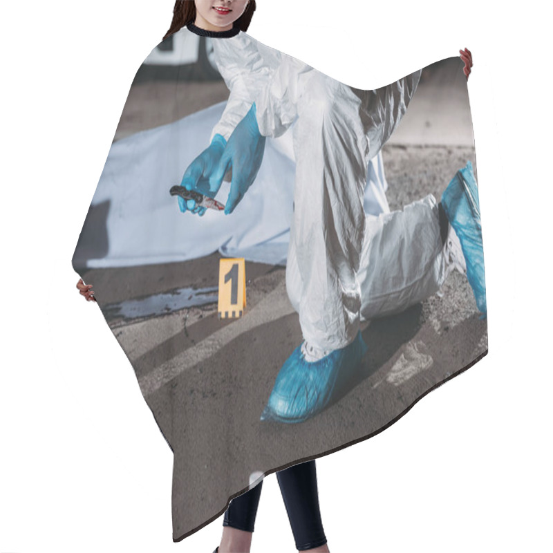 Personality  Cropped Image Of Criminologist In Latex Gloves And Protective Suit Holding Knife Above Blood On Ground Near Corpse In Body Bag At Crime Scene  Hair Cutting Cape