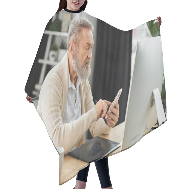 Personality  Handsome Senior Man Interacts With His Smartphone While Seated At A Desk With A Computer. Hair Cutting Cape