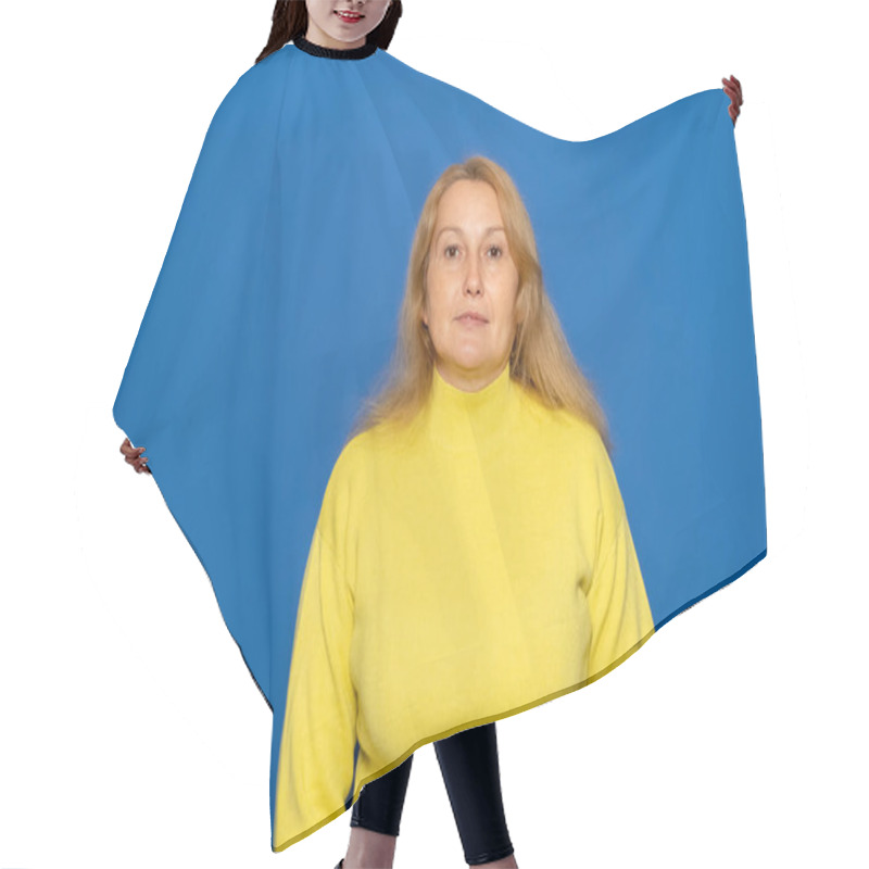 Personality  Horizontal Image Of A Beautiful Brown-haired Caucasian Woman Looking Straight Ahead At The Camera Wearing A Yellow Sweater On A Blue Background. Emotions Concept Hair Cutting Cape