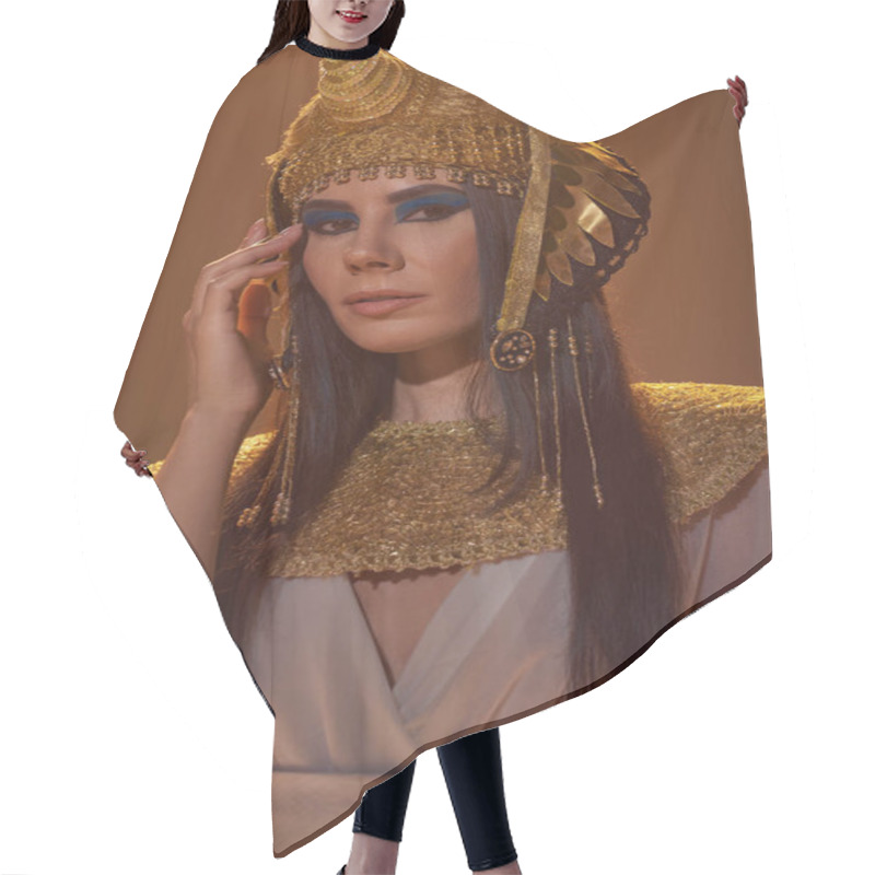 Personality  Portrait Of Brunette Woman In Traditional Egyptian Look And Bold Makeup Standing Isolated On Brown Hair Cutting Cape