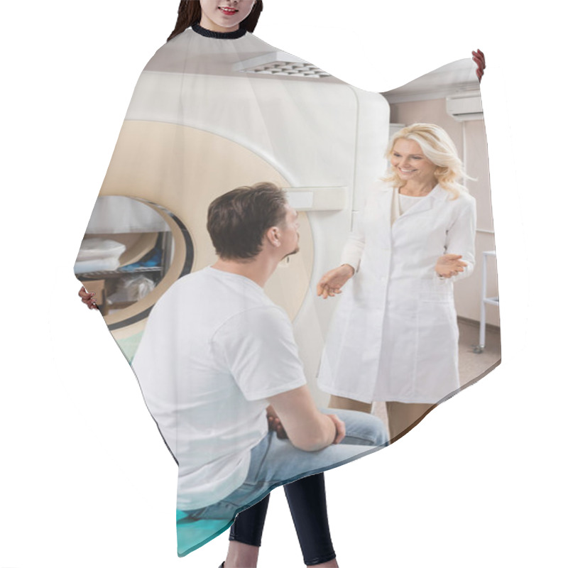 Personality  Smiling Blonde Radiologist Talking To Brunette Man Sitting Near Computed Tomography Scanner Hair Cutting Cape