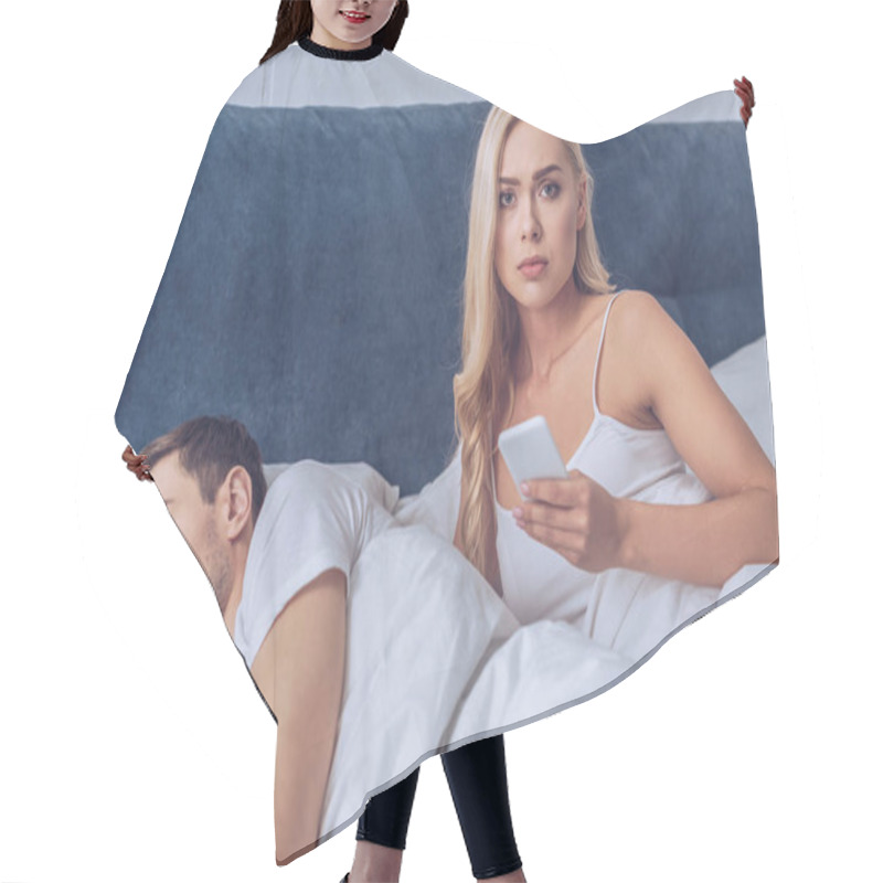 Personality  Unhappy Young Woman Holding Smartphone And Looking At Camera While Boyfriend Sleeping In Bed, Distrust Concept Hair Cutting Cape