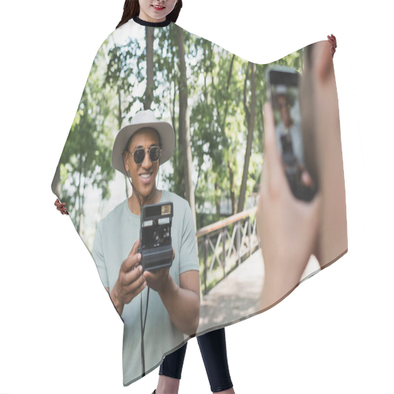 Personality  Blurred Man With Smartphone Taking Photo Of Carefree African American Tourist In Sunglasses Posing With Vintage Camera In Park Hair Cutting Cape