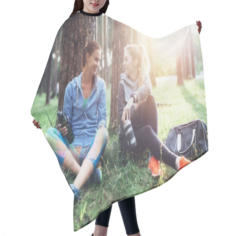 Personality  Two Young Women In Sportswear Sitting Under Trees In The Forest Drinking Water, Talking And Resting After Training Outdoors Hair Cutting Cape