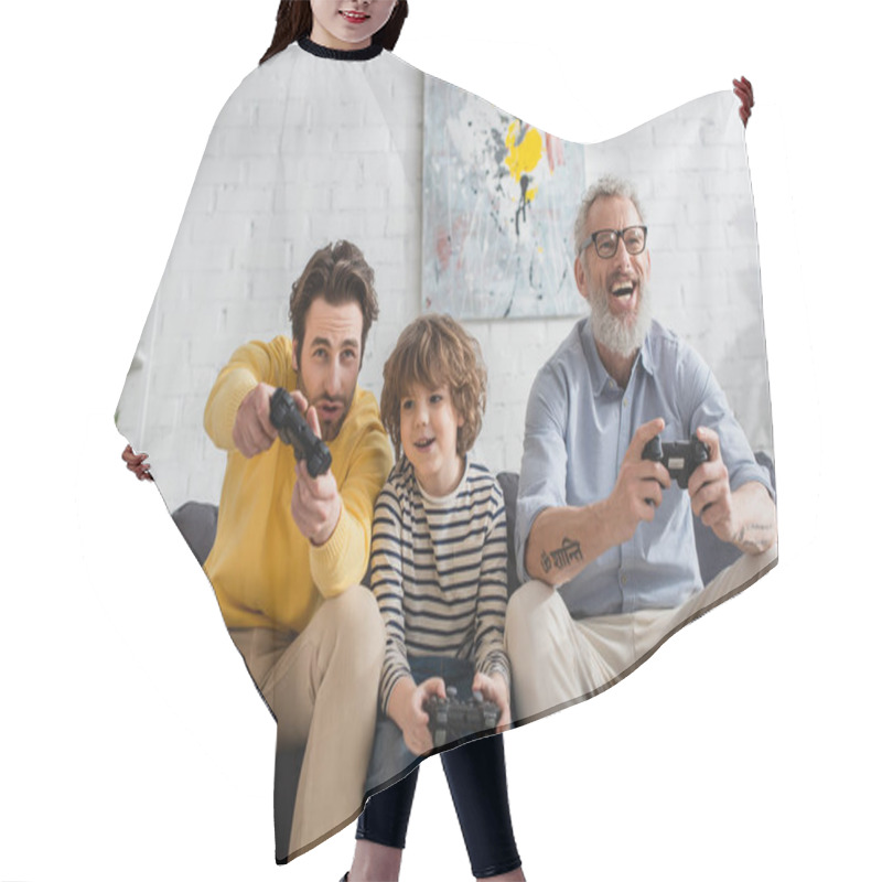 Personality  KYIV, UKRAINE - APRIL 12, 2021: Smiling Kid Playing Video Game With Father And Grandfather  Hair Cutting Cape