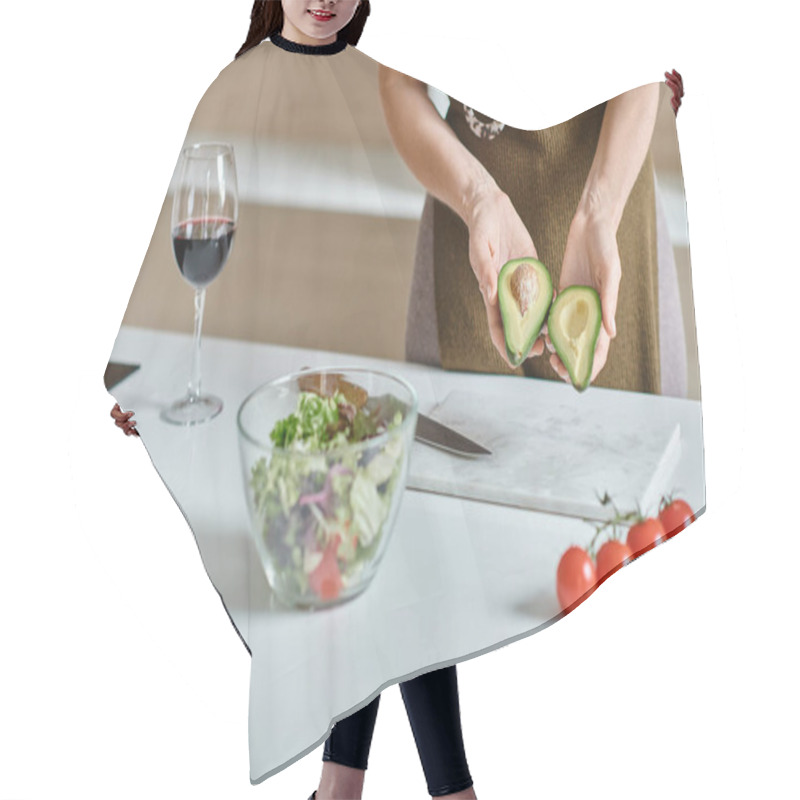 Personality  Cropped Woman Holding Fresh Avocado Halves Near Salad In Bowl And Glass Of Red Wine On Countertop Hair Cutting Cape