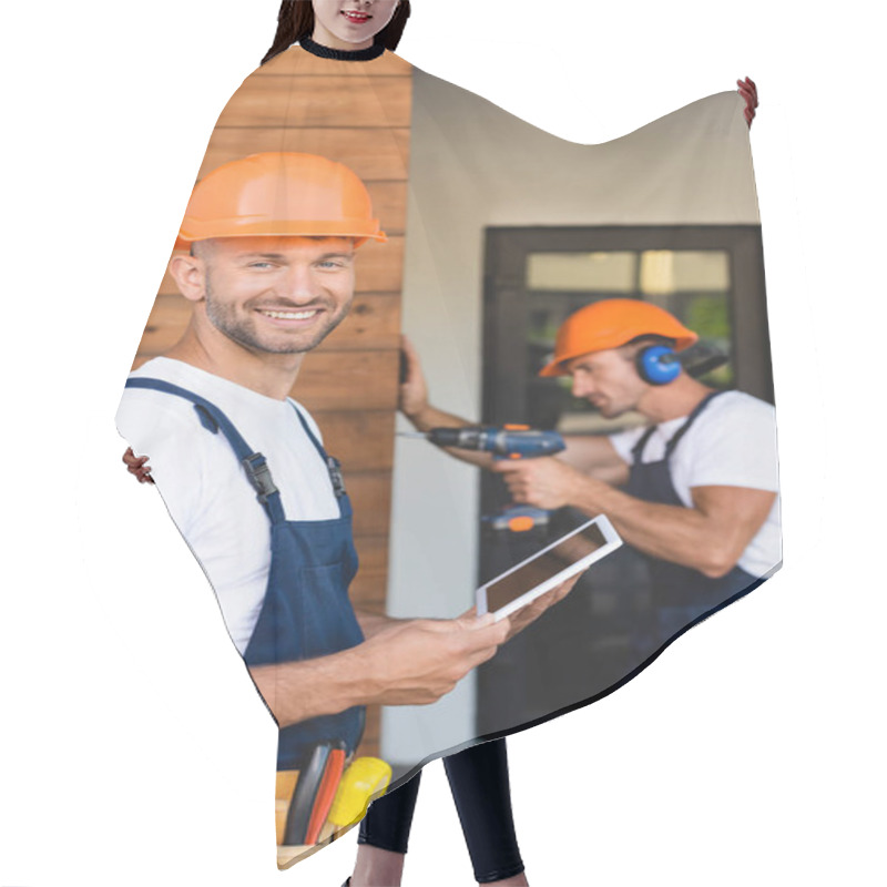 Personality  Selective Focus Of Builder Holding Digital Tablet Near Colleague Working With Electric Screwdriver On Facade Of Building  Hair Cutting Cape