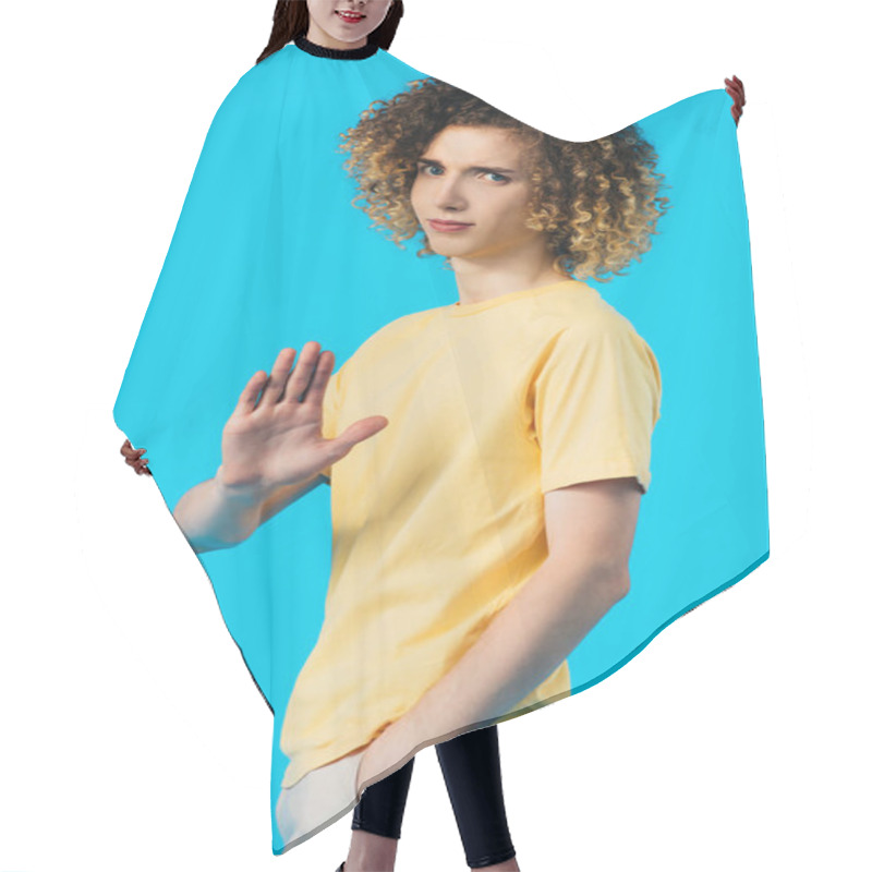 Personality  Upset Curly Teenager With Hand In Pocket Showing Stop Gesture Isolated On Blue Hair Cutting Cape