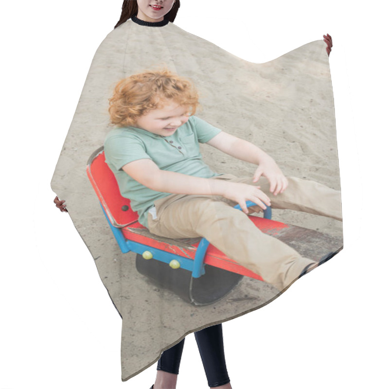 Personality  High Angle View Of Cheerful Boy Riding Seesaw In Amusement Park Hair Cutting Cape