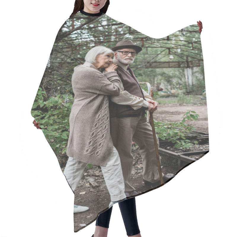 Personality  Sad Senior Woman Standing With Retired Husband In Hat And Glasses  Hair Cutting Cape