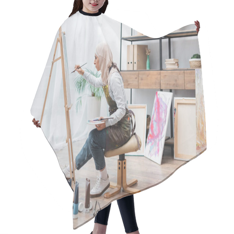 Personality  Side View Of Muslim Woman Sitting On Chair And Drawing On Easel At Home Hair Cutting Cape