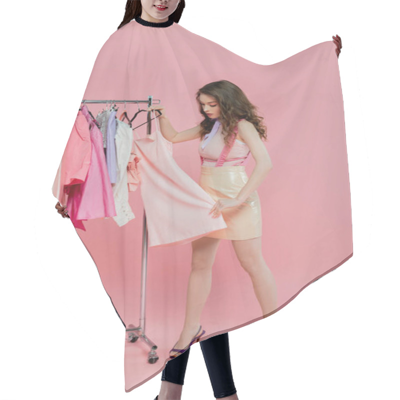 Personality  Wardrobe Essentials, Beautiful Young Woman With Wavy Hair Choosing Clothes, Pretending To Be A Doll, Standing Near Clothes Rack, Standing On Pink Background, Full Length  Hair Cutting Cape