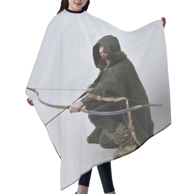 Personality  Full Length  Portrait Of  Young Handsome Man  Wearing  Medieval Celtic Adventurer Costume With Hooded Cloak, Holding  Archery Bow And Arrow, Isolated On Studio Background. Hair Cutting Cape