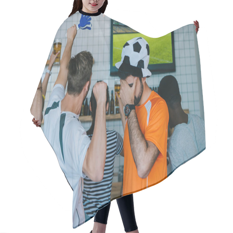 Personality  Frustrated Young Man In Soccer Ball Hat And Fan T-shirt Holding Covering Eyes By Hand Palm While His Friends Celebrating And Doing Yes Gestures During Watch Of Soccer Match On Tv Screen At Bar  Hair Cutting Cape