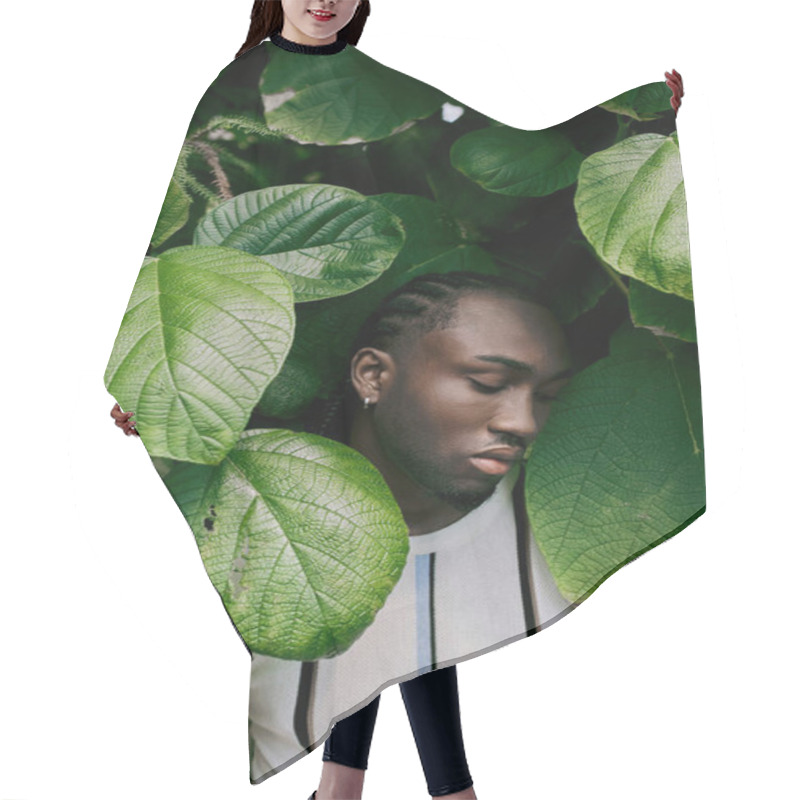 Personality  A Stylish African American Man Stands Poised With Closed Eyes Amidst Lush Green Leaves. Hair Cutting Cape