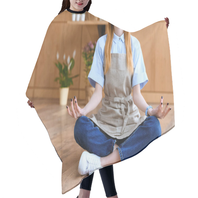 Personality  Cropped Shot Of Smiling Young Florist In Apron Sitting In Lotus Position On Floor  Hair Cutting Cape