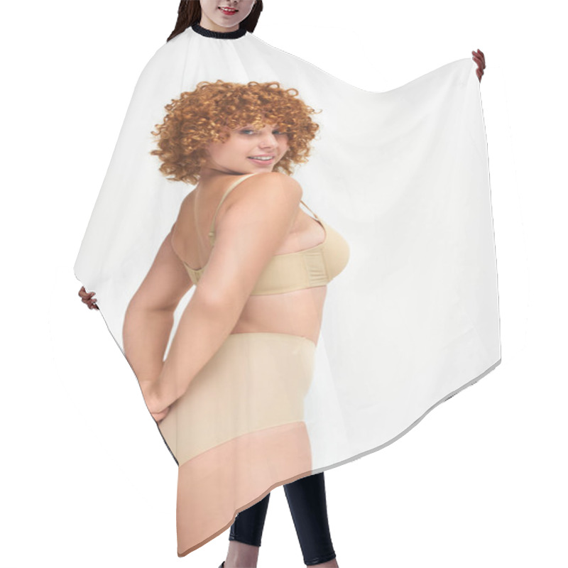 Personality  Curvy And Redhead Woman In Taupe Underwear With Hands Behind Back Smiling At Camera On White Hair Cutting Cape