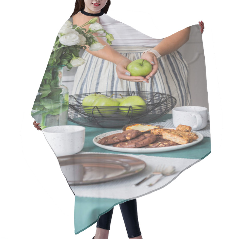 Personality  Woman With Green Apple In Her Hands Standing Next To Kitchen Table With Cookies On Plate And Coffee Mugs Hair Cutting Cape