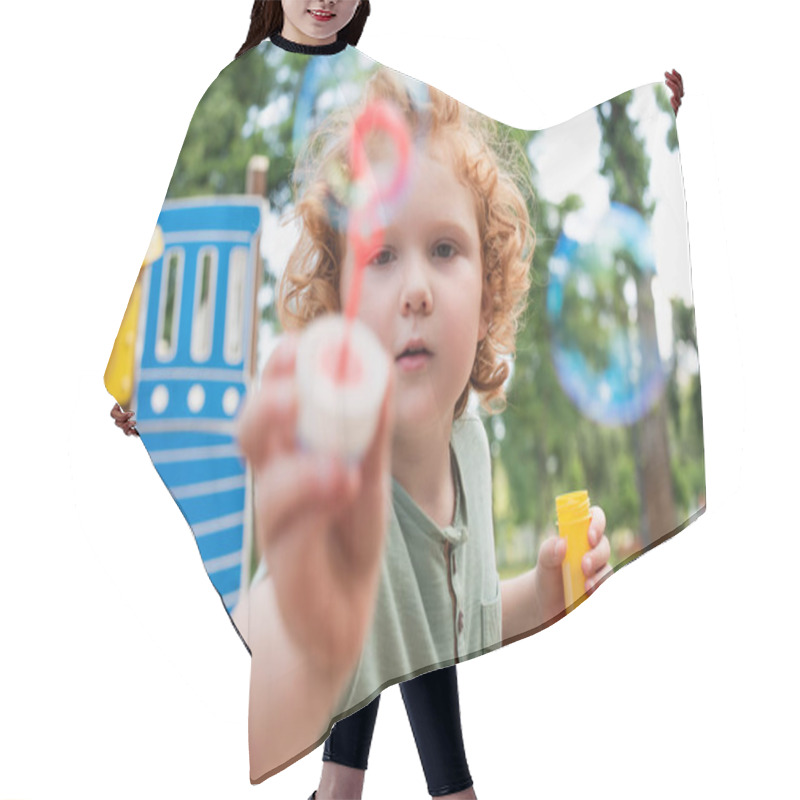 Personality  Redhead Boy Looking At Camera And Showing Blurred Bubble Blower Hair Cutting Cape