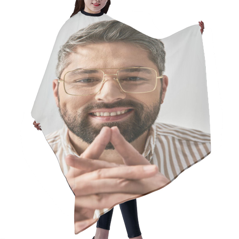 Personality  A Bearded Man In Glasses And A Striped Shirt Poses Elegantly On A Grey Background In A Studio Setting. Hair Cutting Cape