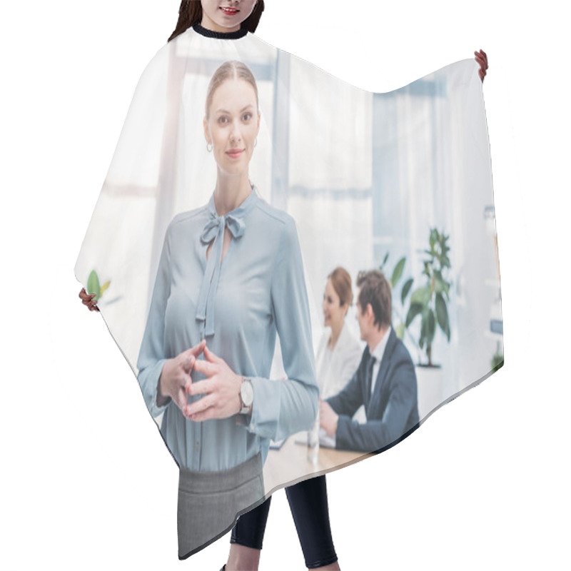 Personality  Cheerful Woman Standing With Clenched Hands Near Coworkers In Office  Hair Cutting Cape