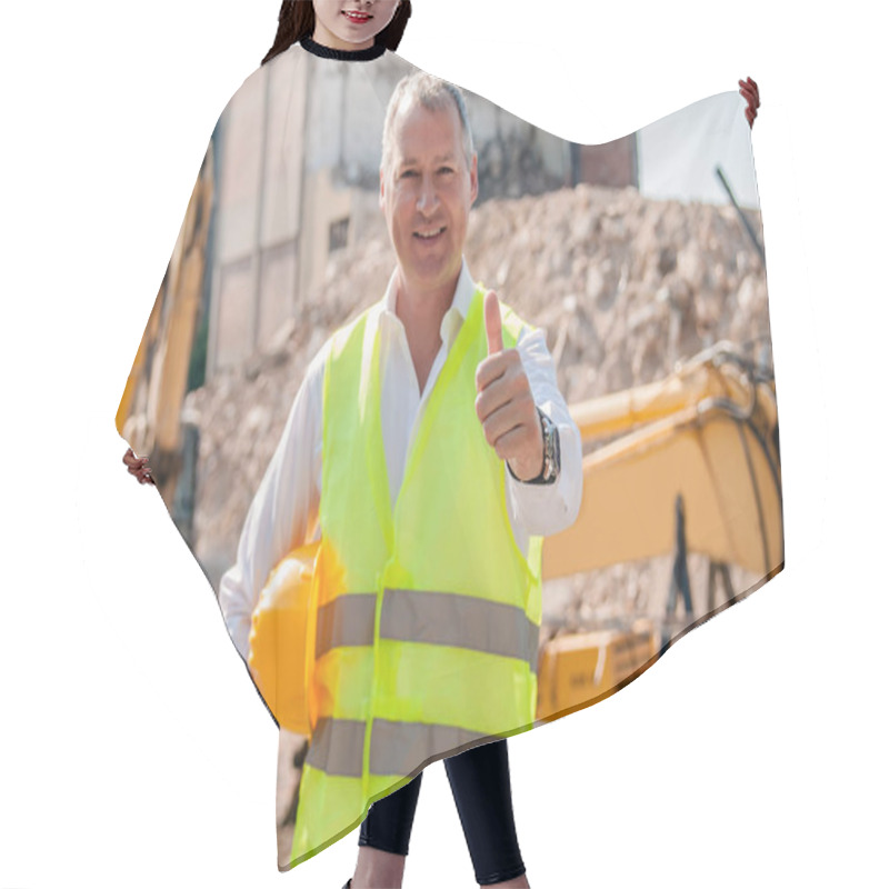 Personality  Portrait Of Smiling Civil Engineer Holding Hardhat And Showing Thumb Up Gesture On Construction Site Hair Cutting Cape